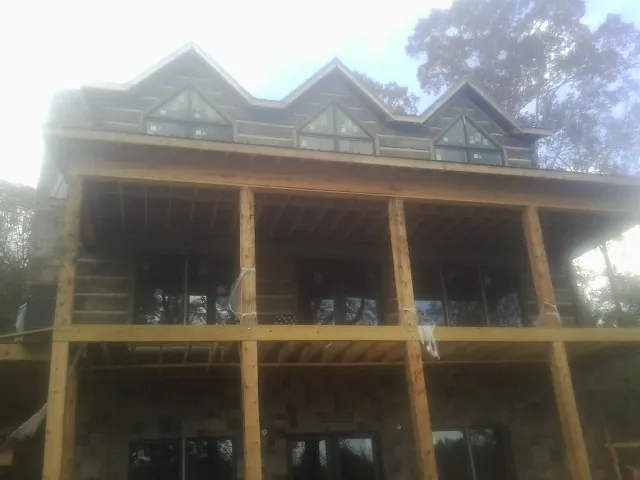 Dormers and porch framing on a large log home under construction — Roof Coating work by our crew in Sand Coulee