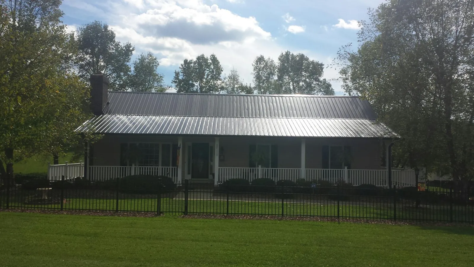 Gray metal roof on a brick ranch with a full width front porch — Gutter Guard Installation work by our crew in Sand Coulee