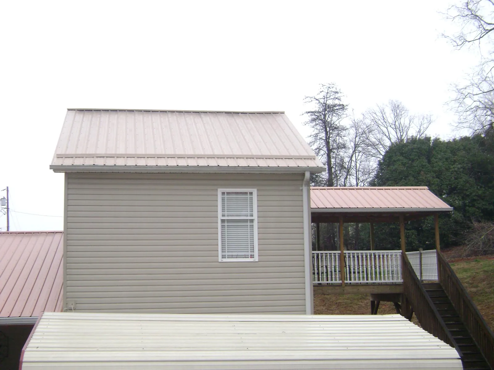 Tan metal roofs on a two story addition and attached porch, from a Roof Replacement job in Sand Coulee