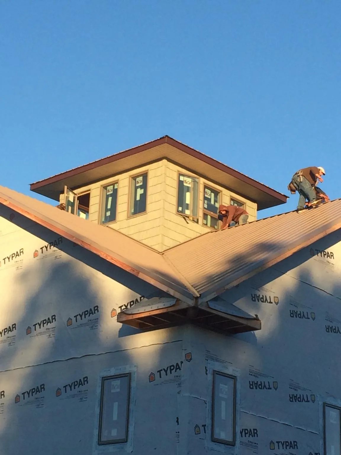 Roofers working around a rooftop cupola on a new metal roof at sunset — Roof Waterproofing in Sand Coulee by Roofing Brothers